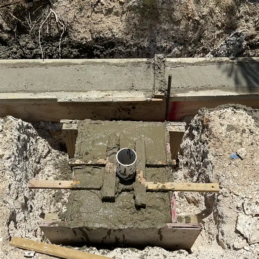 Concrete footing cast in timber formwork with a service sleeve set into it