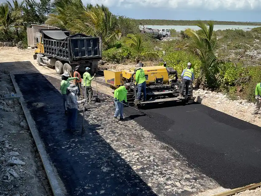 Paving machine laying hot asphalt with the crew working behind it
