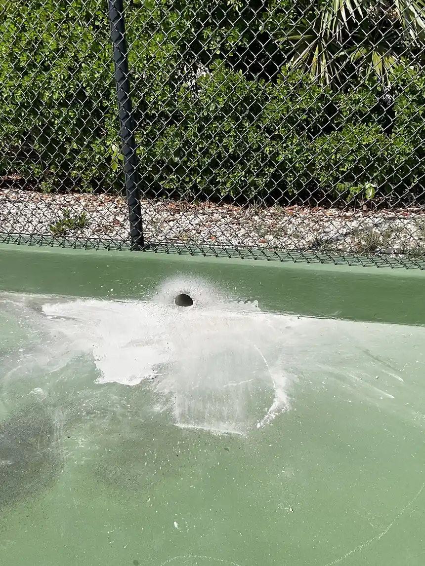 Blistered patch of surface raised around a drain outlet on a court