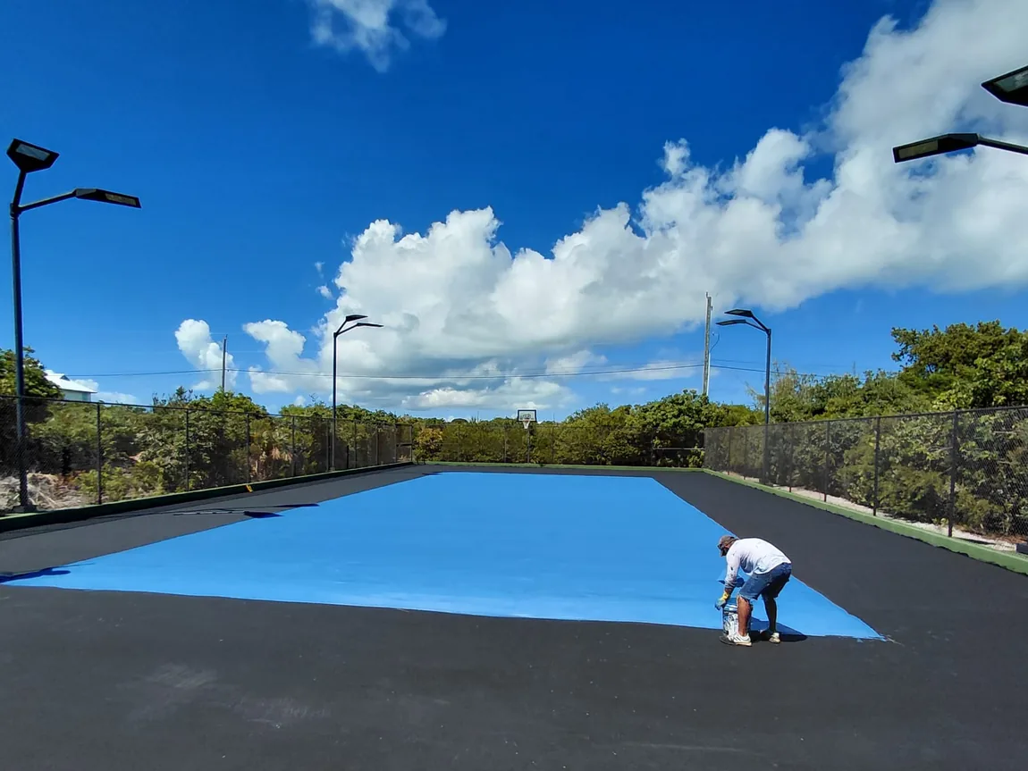Fresh coat being spread across a court surface during resurfacing work